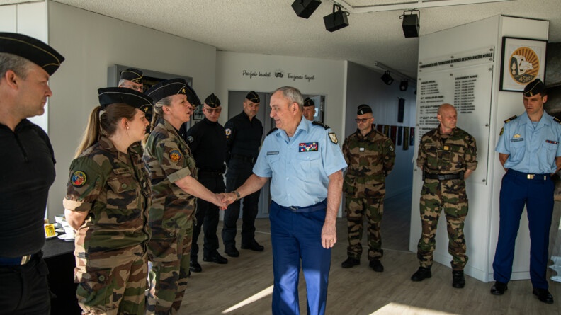 Agrandir l'image Le DGGN serre la main d'une gendarme en treillis kaki. Sur la même rangée se trouvent une autre gendarme en kaki et cinq gendarmes mobiles en tenue d'intervention. Dans le fond deux officiers en kaki et un autre en bleu.