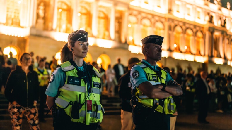 Deux gendarmes devant la foule et la façade éclairée du château de chambord, de nuit