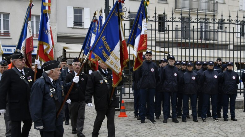 Agrandir l'image Des portes drapeaux et des jeunes du SNU devant une grille sur les pavés