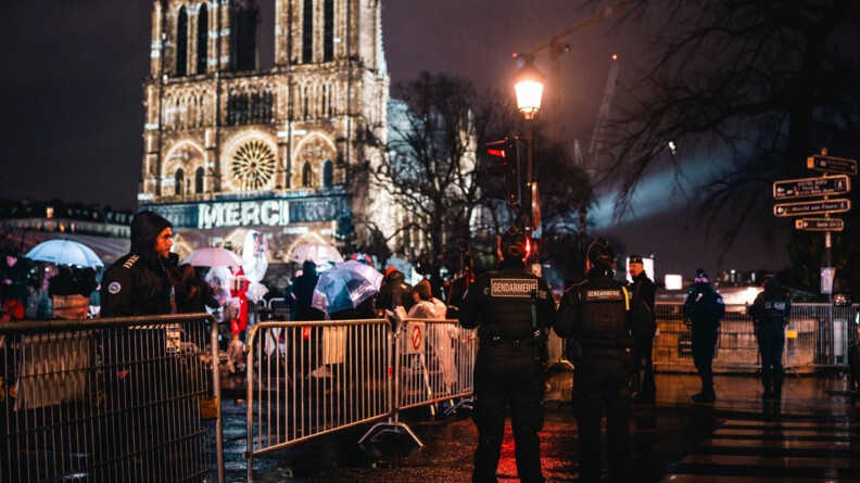 Photo de gendarmes mobile devant le parvis de Notre-Dame. Derrière sur la cathédrale, il est écrit "MERCI"