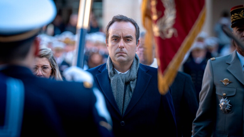 Photo de Sébastien Lecornu, ministre des Armées, debout, face à un militaire tenant un drapeau, lors de la prise d'arme du 7 janvier 2025 à Paris.