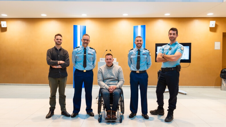 Trois gendarmes, un civil et un ancien gendarme en fauteuil roulant posent devant l'objectif.