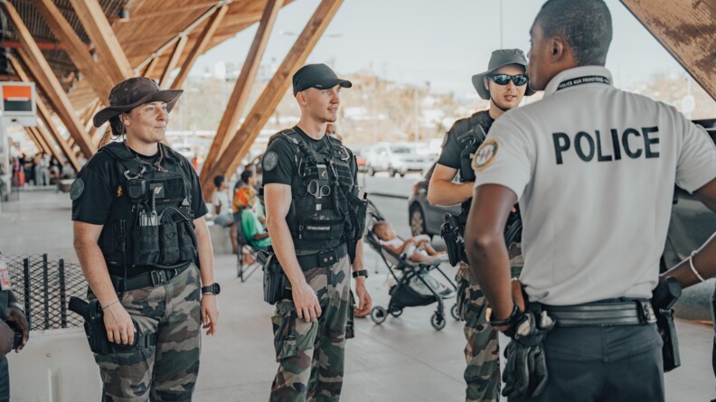 Trois gendarmes avec un policier de dos &agrave; droite dans un a&eacute;roport &agrave; Mayotte