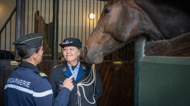 La commandante Kmar discute avec une femme de la gendarmerie nationale, devant un cheval dont la t&ecirc;te d&eacute;passe de son box