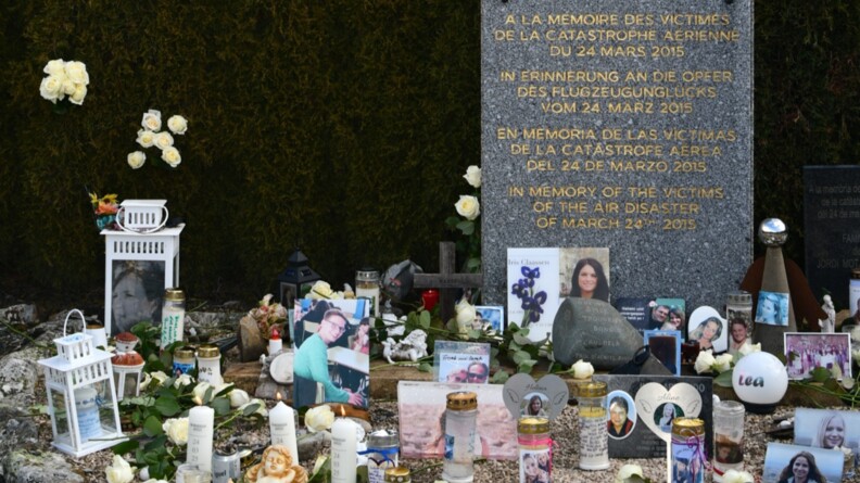 Une pierre tombale avec devant de nombreuses photos des victimes du crash et sur la plaque "A la m&eacute;moire des victimes de la catastophe a&eacute;rienne du 24 mars 2015"