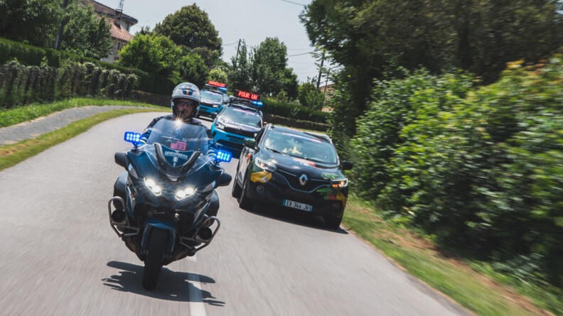 Un gendarme de l'escadron motocyliste de la Garde r&eacute;publicaine avec en fond, la caravane gendarmerie du Tour de France