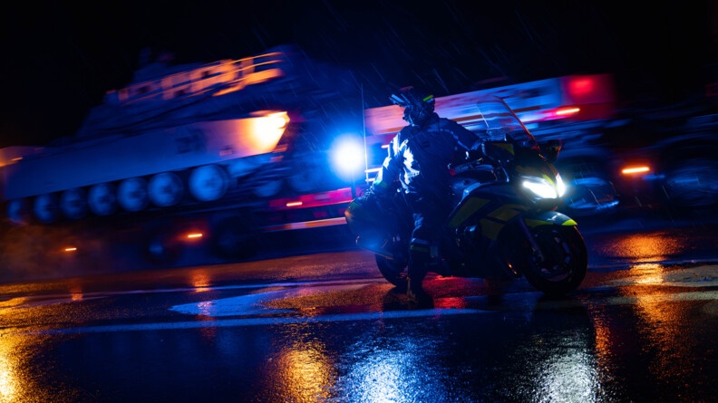 Un motocycliste de la gendarmerie avec derrière le convoi en train de passer.