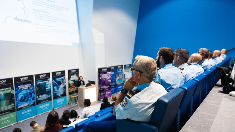 Dans un amphith&eacute;atre bleu, des g&eacute;n&eacute;raux, des colonels et d'autres gendarmes &eacute;coutent attentivement la pr&eacute;sentation du nouveau projet d'Ynov-Campus.