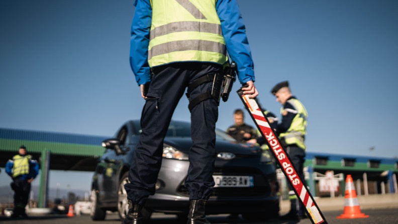 Agrandir l'image Photo d'un gendarne de dos, positionné devant une voiture, au niveau d'un péage autoroutier