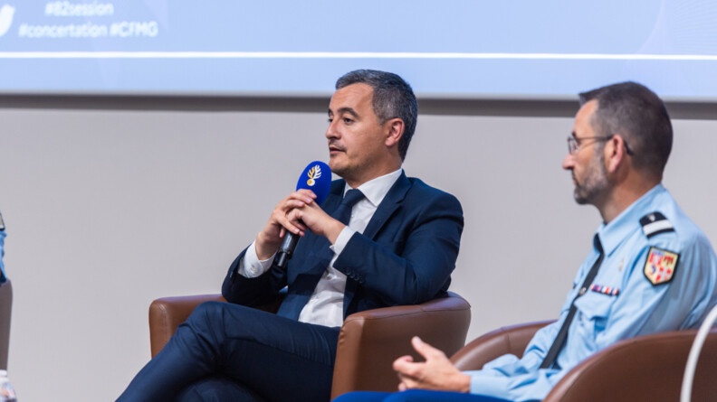 Agrandir l'image Le ministre de l'Intérieur Gérald Darmanin avec un micro. A sa gauche, un officier de gendarmerie.