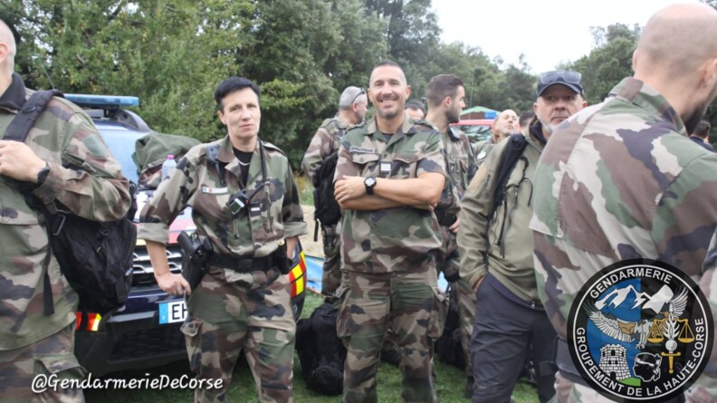 Des militaires sont réunis devant un véhicule de la gendarmerie, dans un espage extérieur arboré. A doite de la photo, un écusson a été apposé, qui porte la mention "Gendarmerie - Groupement de la Haute-Corse"
