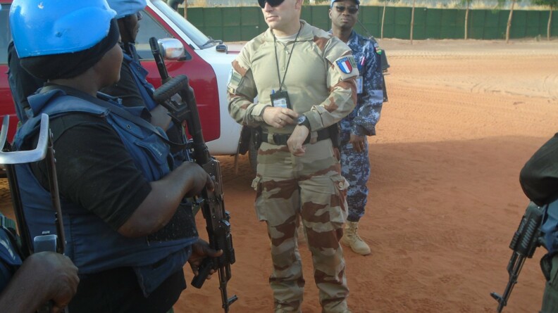 Agrandir l'image Un gendarme en mission ONU au Mali avec un véhicule de l'ONU et des policiers maliens.