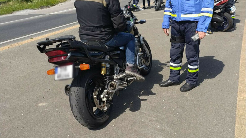 Agrandir l'image Un motocycliste de dos contrôlé par un gendarme.