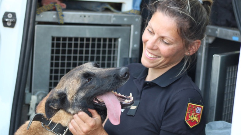Agrandir l'image La photo représente une gemme gendarme, blond, souriante, tenant contre elle un berger belge malinois dressé contre elle.