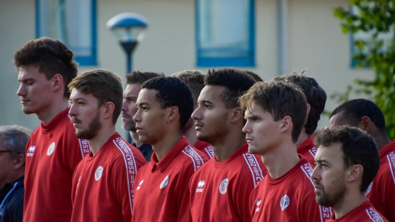Gros plan sur la première rangée de six sportifs vêtus d'un sweat rouge.