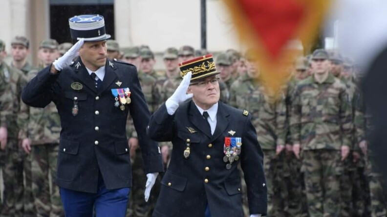 Un général et un colonel saluent les troupes. En arrière plan, des gendarmes en treillis au garde-à-vous.