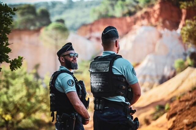 Deux gendarmes, l'un de dos, l'autre de trois-quart, dans les Ocres de Rustrel, dans le Vaucluse.