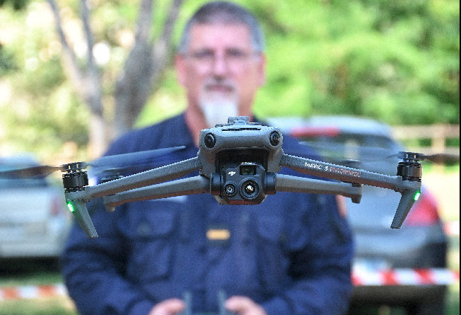 La photo représente un télépilote de drone de la gendarmerie, engagé à l'occasion du festival Garorock 2025. L'homme tient une télécommande de ses deux mains. Au premier plan, sur la photo, apparaît le drone, volant à hauteur du visage du télépilote.
