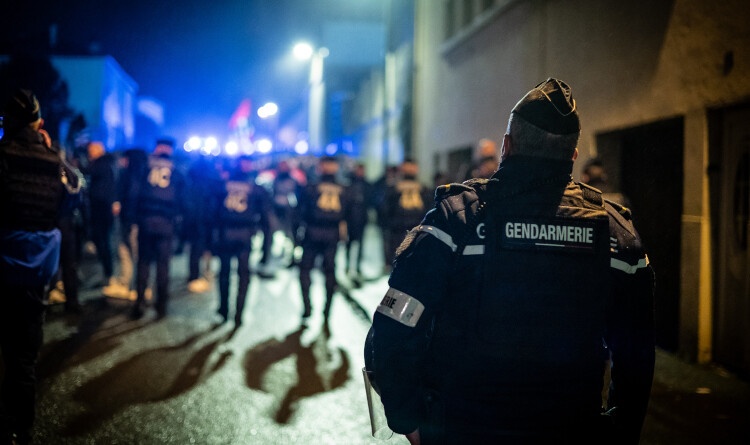 Gendarme de dos avec rangée de CRS devant.