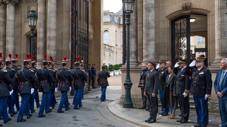 Militaires de la Garde républicaine pénétrant dans la cour de l'Elysée. A la droite de l'entrée se tiennent le chef de l'Etat ainsi que des personnalités officielles