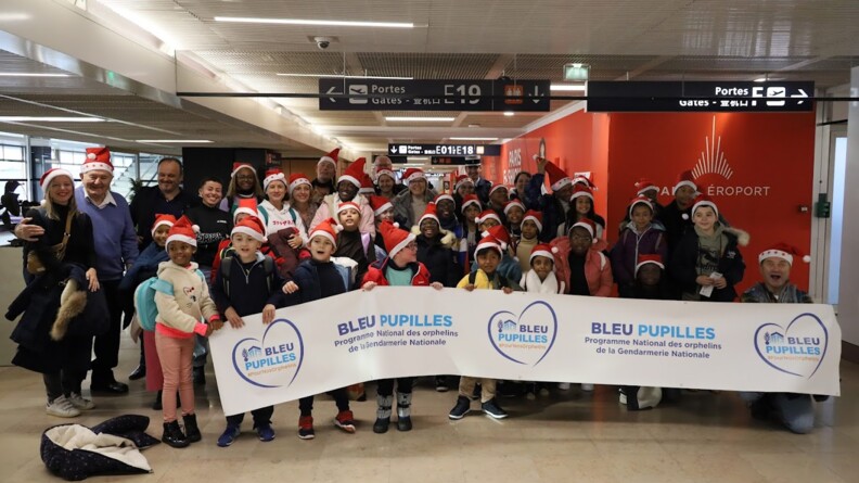 Agrandir l'image Les enfants de l'association à l'aéroport avec une banderolle.