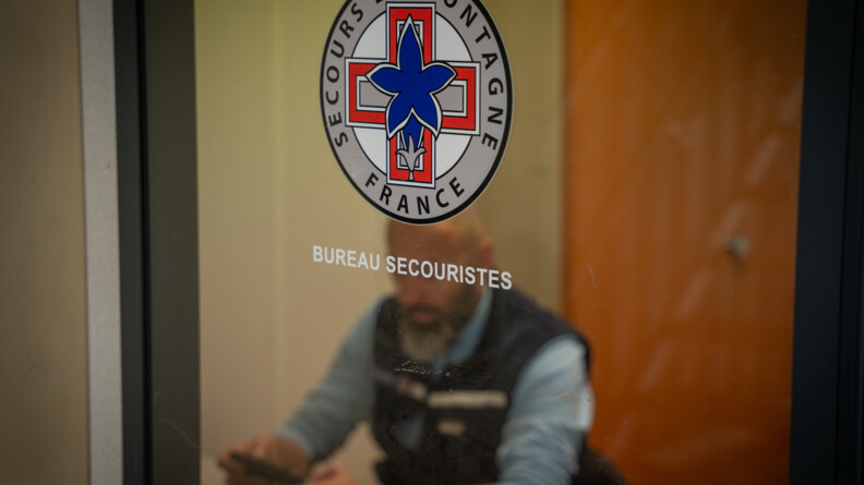En intérieur, un bureau avec une porte vitrée derrière laquelle ont distingue un gendarme. Sur la porte est écrit "Secours en montagne"
