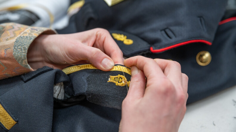 Plan rapproch&eacute; des mains de la couturi&egrave;re cousant une veste de Garde.