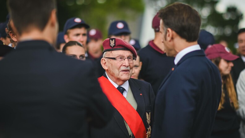 Macron de dos serre la main au vétéran Achille Muller, membre du SAS, dernier parachutiste français