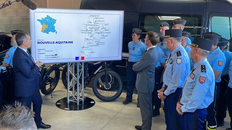 Présentation de la carte des nouvelles brigades de gendarmerie sur un écran, à Tonneins, dans le Lot-et-Garonne. A gauche de l'écran le ministre de l'Intérieur et des Outre-mer, Gérald Darmanin, et une gendarme derrière lui. A droite de l'écran, le président de la République Emmanuel Macron, le général d'armée Christian Rodriguez, directeur général de la gendarmerie nationale, le général de corps d'armée Samuel Dubuis, commandant de la Région de gendarmerie Nouvelle-Aquitaine, et plusieurs gendarmes.