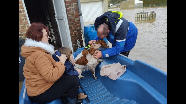 Sur un bateau de la brigade fluviale, un gendarme calme deux chiens assis &agrave; c&ocirc;t&eacute; de leur maitresse et de sa fille.