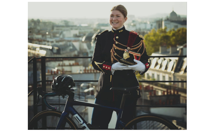 La gendarme Derbesse posant en tenue de garde républicain devant son vélo.