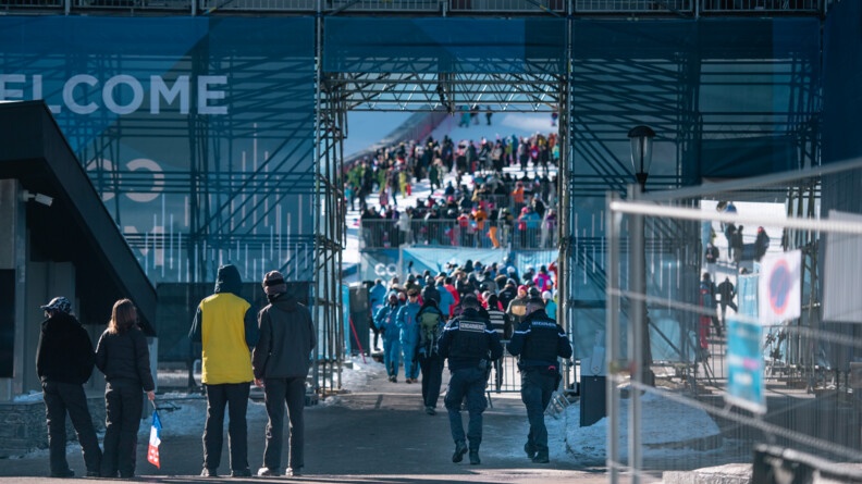 Devant la grande estrade de la piste de l'Eclipse à Courchevel, deux gendarmes vont entrer à l'intérieur de la raquette, le lieu d'arrivée des skieurs, où se trouvent beaucoup de monde.
