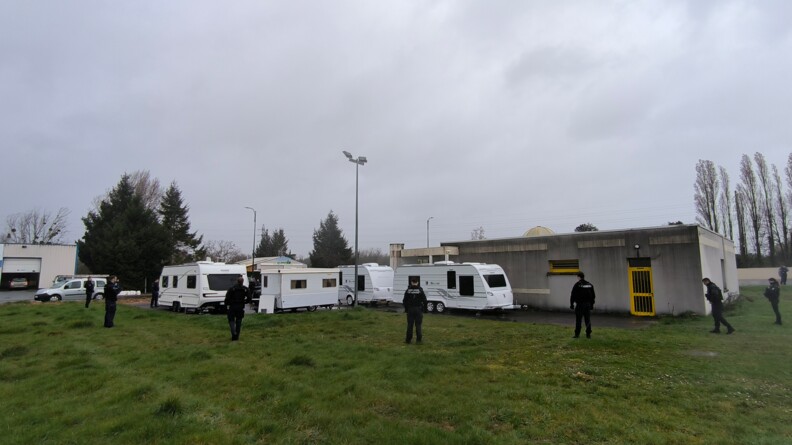 Agrandir l'image Une dizaine de gendarmes de dos, sur un terrain vague encerclant des caravanes.