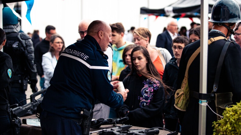 Un gendarme, de dos, présente des armes aux visiteurs des Journées portes ouvertes.
