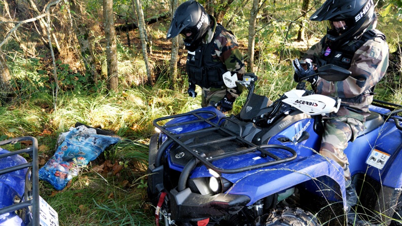 Deux gendarmes en treillis dont un sur un quad gendarmerie ramassent des déchets dans les bois