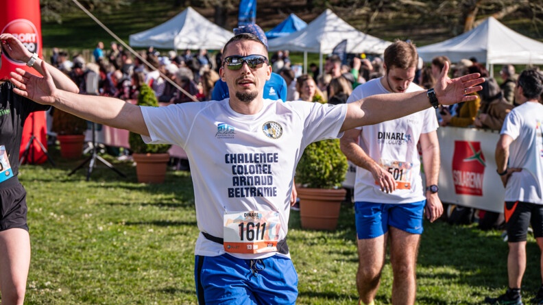 Photo d'un homme, à l'arrivée d'une course, les bras levés à l'horizontal