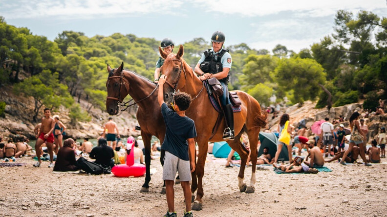 Jeune garçon caressant le cheval d'un cavalier du détachement.