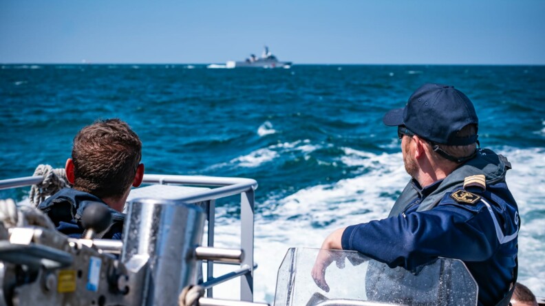 Deux gendarmes sur un bateau en premier plan et dans le fond, se détachant sur le ciel bleu, un autre bateau de la gendarmerie.