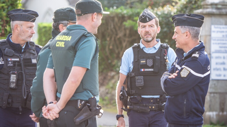 De gauche à droite: un gendarme de profil vers la droite, deux gardes civils mains dans le dos, un gendarme de face et un autre de profil vers la gauche, bras croisés