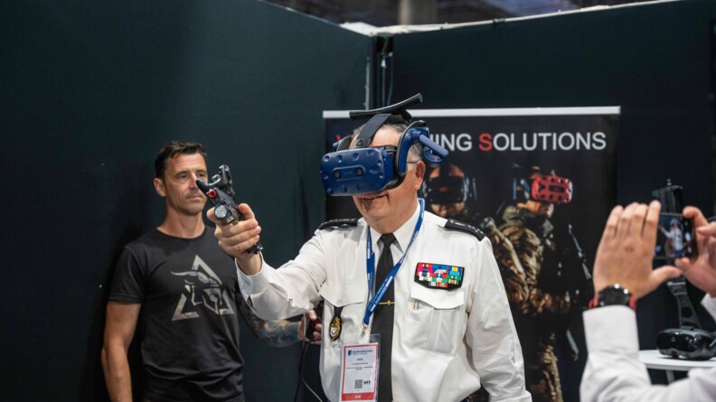 Le DGGN teste une solution d&rsquo;entra&icirc;nement au tir en r&eacute;alit&eacute; virtuelle, dont le Centre national d&rsquo;entra&icirc;nement des forces de gendarmerie (CNEFG) vient de s&rsquo;&eacute;quiper. Il porte un casque &agrave; cet effet et tient un pistolet dans la main droite.