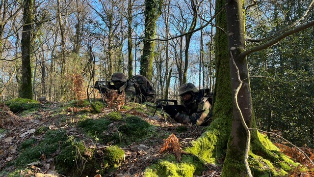 Deux gendarmes, en tenue de combat, dans la for&ecirc;t en entra&icirc;nement allong&eacute;s au sol tenant un FAMAS.