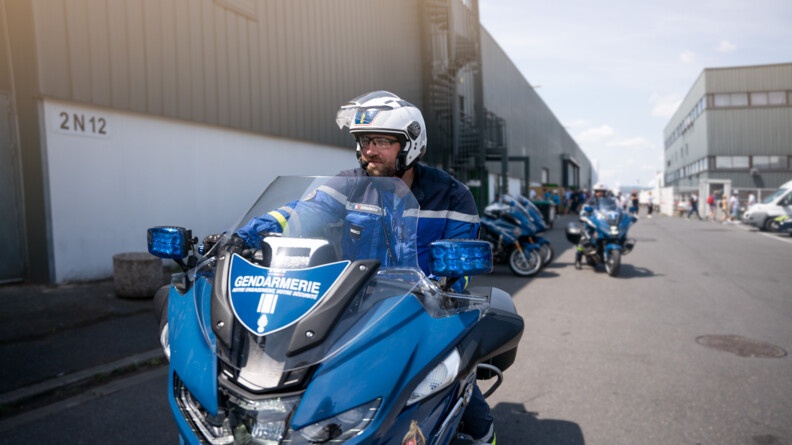Un motard de la Garde républicaine sur sa moto, vu de face et très proche, avec au fond un autre motard en train de stationner sa moto avec les autres