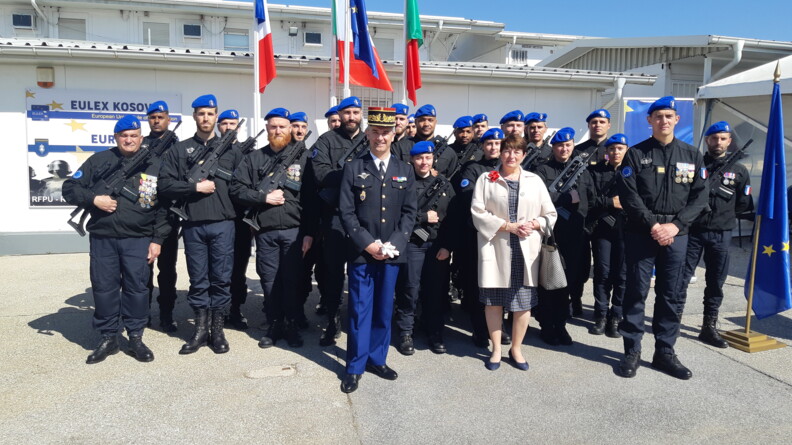 Un groupe d'une vingtaine de gendarmes mobiles arborant le bérêt de la FGE, devant eux un officier général de gendarmerie et une femme en civil