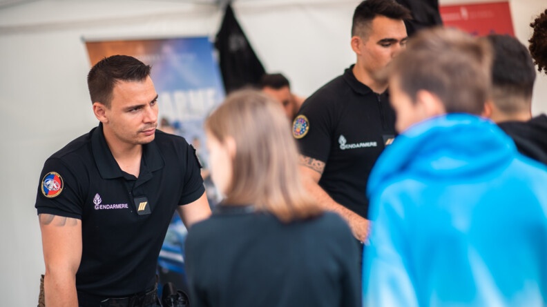 Sur la photo, deux sous-officiers de la gendarmerie en polo noir, &eacute;changent avec des jeunes, venus se renseigner sur les m&eacute;tiers de la gendarmerie.