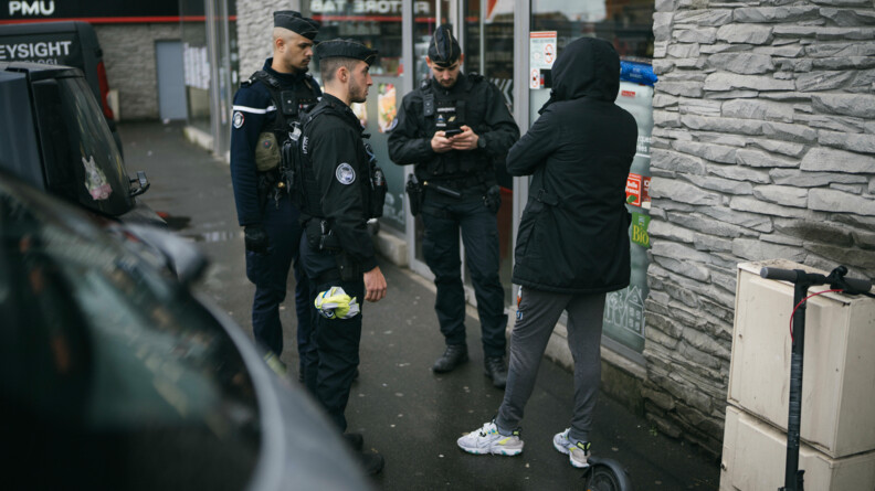 Trois gendarmes procèdent au contrôle d'un piéton au pied de bâtiments