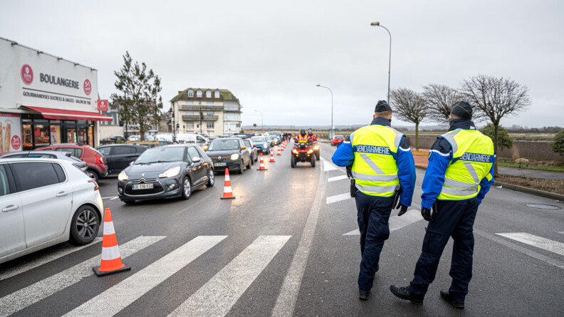 Photo de deux réservistes de dos gérant la gestion du flux. Sur la gauche on peut voir une file de voiture ainsi que deux quads de sapeurs pompiers arriver.