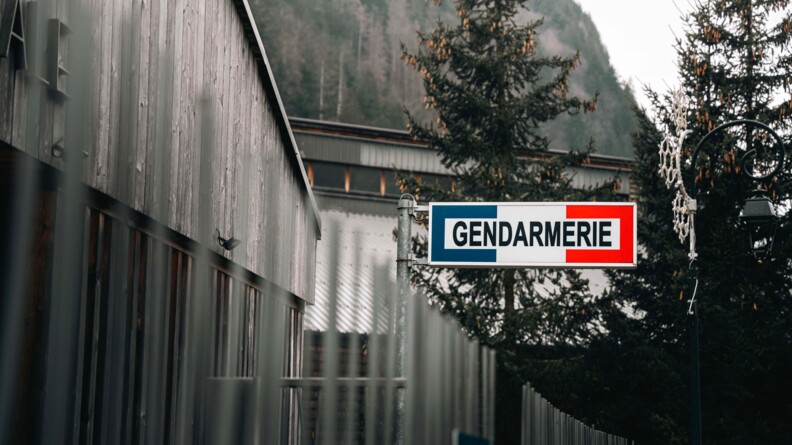 Agrandir l'image Façade d'une brigade de gendarmerie de montagne. On aperçoit la pancarte "gendarmerie" de couleur bleu, blanc et rouge, et la montagne se dressant en arrière plan.