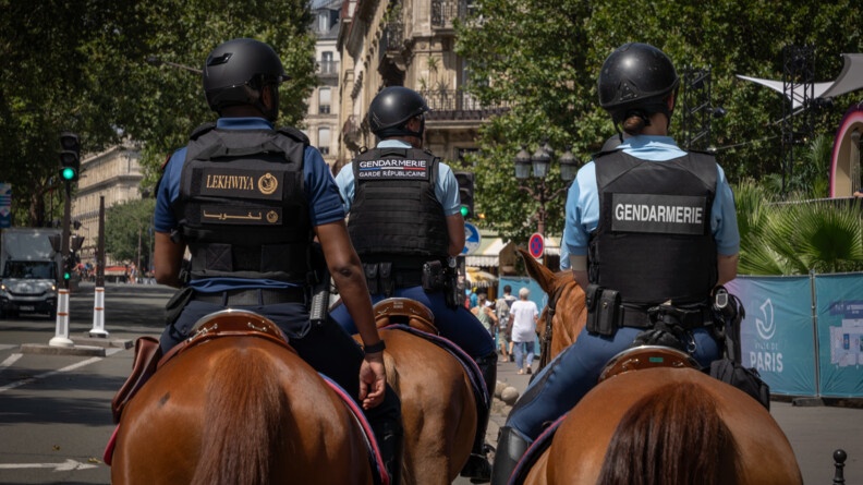 De dos, deux cavaliers de la garde républcaine et à gaucher un cavalier de la police du Qatar marchent dans une rue