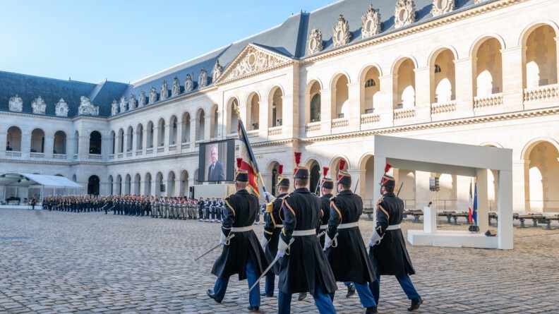 Dans la cour des invalides, des gendarmes de la Garde marchent.