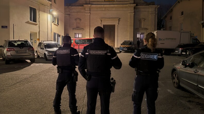 Trois gendarmes sur une place au pied d'une église